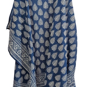 Peut inclure: Une écharpe en coton bleu avec un motif de feuilles blanches. L'écharpe a une bordure avec un motif floral.