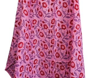 May include: A pink cotton scarf with a floral print in shades of red and purple. The scarf has a border with a repeating pattern.