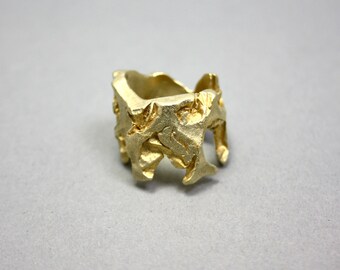 May include: A gold-colored ring with a textured, irregular surface. The ring is made of metal and has a unique, organic design.