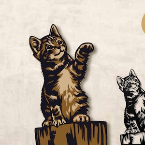 Op de afbeelding: Twee katvormige 3D gelaagde SVG-ontwerpen. Eén is bruin en zwart, de andere is zwart en wit. Beide katten worden afgebeeld met een poot omhoog. De ontwerpen staan op een lichte achtergrond. Tekst op de afbeelding zegt "3D LAYERS SVG" en "Art 4 You Space".
