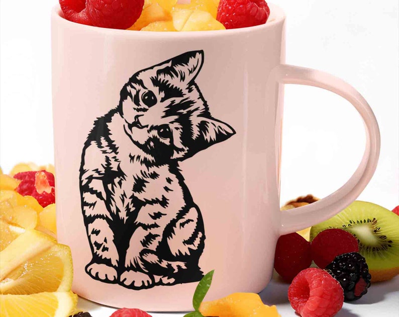 May include: A pink ceramic mug with a black silhouette of a kitten looking over its shoulder. The mug has a large handle and is decorated with a black and white kitten design.