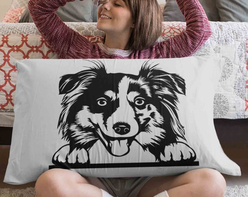 May include: A white pillow with a black and white illustration of a border collie dog peeking over the top. The dog has a playful expression and is looking directly at the viewer.