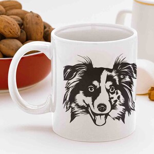 May include: White ceramic mug with a black and white illustration of a dog's face. The dog has black fur, white markings, and a tongue sticking out.