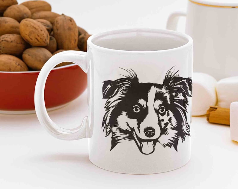 May include: White ceramic mug with a black and white illustration of a dog's face. The dog has black fur, white markings, and a tongue sticking out.