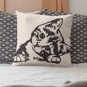 May include: A white pillow with a black and white illustration of a cat peeking out from the side. The cat has a striped pattern and is looking directly at the viewer.