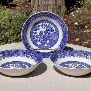 May include: Three-piece set of blue and white Willow pattern serving bowls. The bowls have a classic design with a detailed landscape scene in the center and a patterned border. The bowls are made of ceramic.