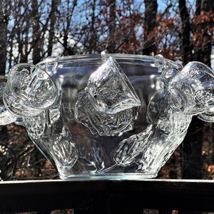 May include: A clear glass punch bowl with a floral design and six matching cups hanging from the rim.