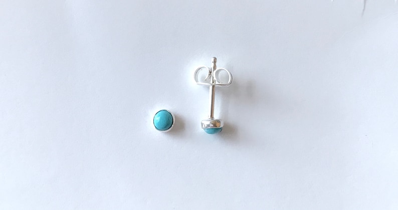 Puede incluir: Un par de pendientes de plata con piedras turquesa. Los pendientes se muestran sobre un fondo blanco.