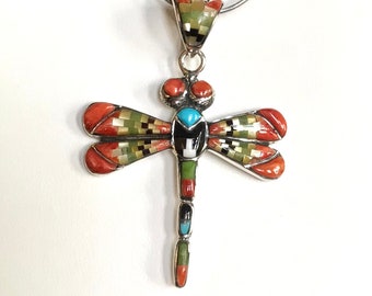 Può includere: Un ciondolo a forma di libellula in argento con pietre rosse, verdi, turchesi e nere. La libellula è dettagliata con intricati motivi a mosaico.