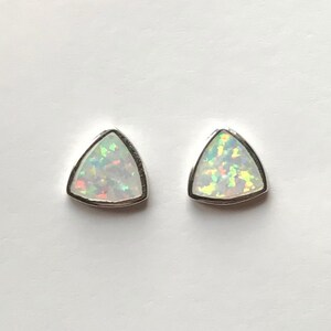 Puede incluir: Un par de pendientes de triángulo de plata con piedras de ópalo blanco.