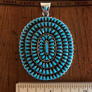 Pu&ograve; includere: Un ciondolo in turchese e argento sterling con un gruppo di pietre turchesi di forma ovale. Il ciondolo misura circa 2,5 cm di diametro.
