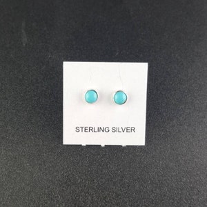 Puede incluir: Un par de pendientes de plata de ley con piedras turquesa. Los pendientes est&aacute;n en una tarjeta blanca con las palabras "Sterling Silver" impresas en ella.