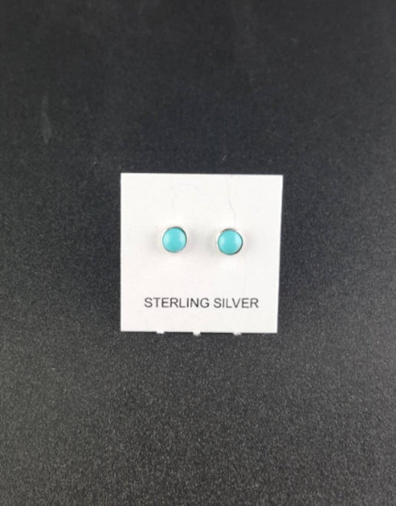 Puede incluir: Un par de pendientes de plata de ley con piedras turquesa. Los pendientes est&aacute;n en una tarjeta blanca con las palabras "Sterling Silver" impresas en ella.