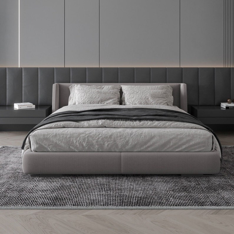 Pode incluir: Uma cama com uma cabeceira estofada em cinza, um edredom de linho branco e uma manta preta. A cama est&aacute; sobre um tapete com padr&atilde;o preto e branco em um quarto moderno.