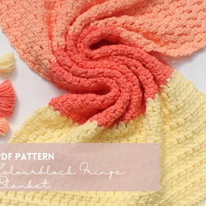 Puede incluir: Una manta de crochet con un patrón de bloques de color en amarillo y naranja. La manta tiene un borde de flecos y está hecha con un punto texturizado. El texto "PDF PATTERN Colourblock Fringe Blanket" está en un rectángulo rosa.