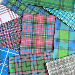 Può includere: Una collezione di fogli rettangolari sovrapposti che presentano vari motivi colorati a tartan e a quadri. I design includono linee che si intersecano in tonalità di rosso, blu, verde, giallo, bianco e viola, creando una varietà di motivi a griglia.