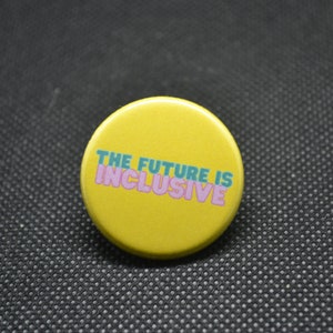 May include: A yellow button with the text "THE FUTURE IS INCLUSIVE" in pink and teal lettering.