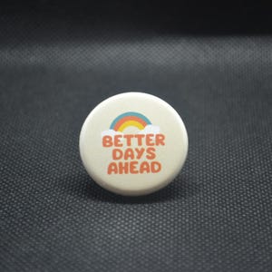 May include: White button with a rainbow and the text "Better Days Ahead" in orange.