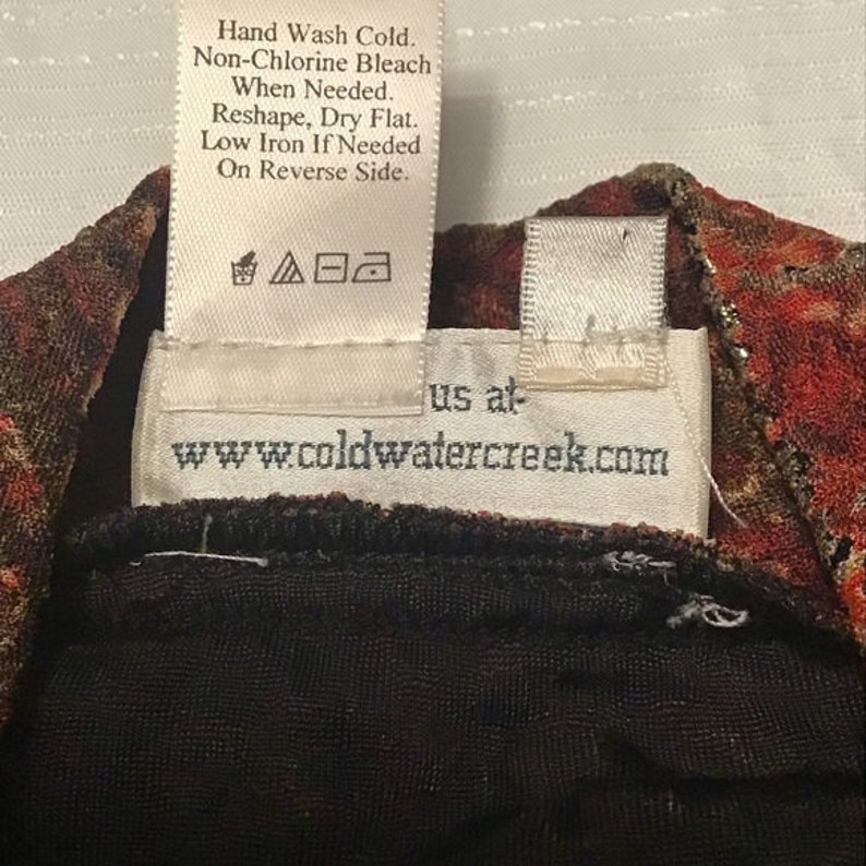 Pode incluir: Uma etiqueta branca com texto preto que diz "Hand Wash Cold. Non-Chlorine Bleach When Needed. Reshape, Dry Flat. Low Iron If Needed On Reverse Side." A etiqueta tamb&eacute;m tem um s&iacute;mbolo para lavar, secar e passar a ferro. Abaixo da etiqueta, h&aacute; uma etiqueta branca com texto preto que diz "us at www.coldwatercreek.com".