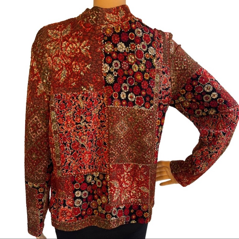 Pode incluir: Uma camisa de manga comprida com gola alta, com um padr&atilde;o vermelho, dourado e preto.