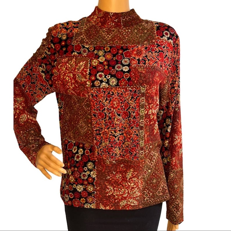Pode incluir: Uma blusa de manga comprida com gola alta e design de patchwork com padr&otilde;es florais vermelhos, pretos, dourados e brancos.