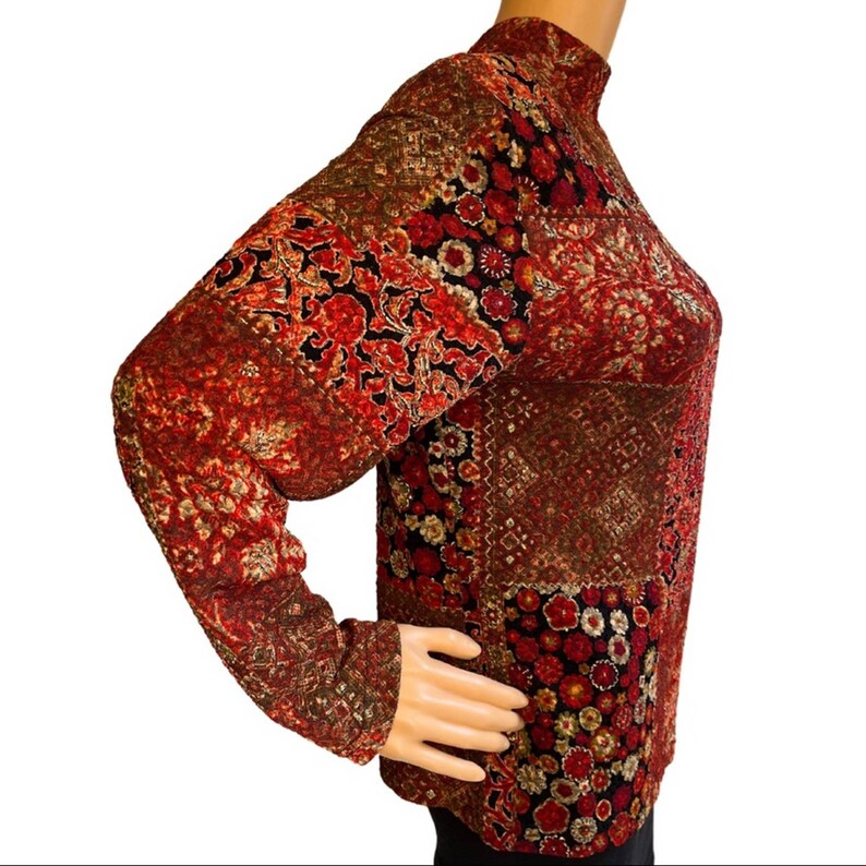 Pode incluir: Uma camisa de manga comprida com gola alta, com um padr&atilde;o vermelho, dourado e preto.