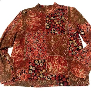 Pode incluir: Uma blusa de manga comprida com gola alta, em padr&atilde;o vermelho, marrom e creme.