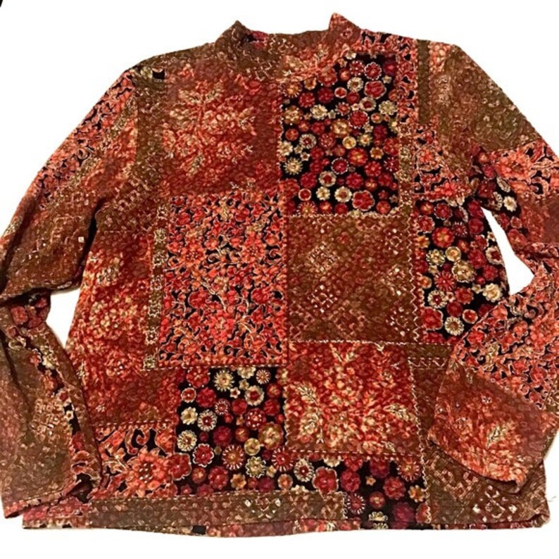 Pode incluir: Uma blusa de manga comprida com gola alta, em padr&atilde;o vermelho, marrom e creme.