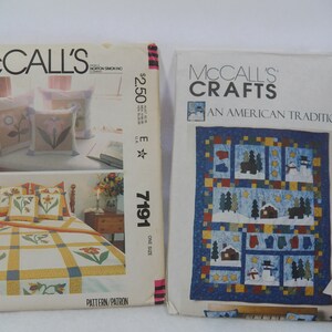 May include: Two vintage McCall's pattern envelopes. One shows a floral bedspread and pillow design, the other a quilt with a winter scene. The quilt pattern is labelled "AN AMERICAN TRADITION". The floral pattern is labelled "7191".