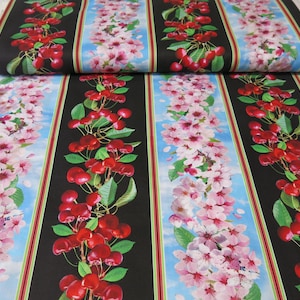 May include: Fabric with a repeating pattern of vertical stripes. Alternating stripes feature cherry blossoms, cherries, and a blue sky background. The cherries are red, and the blossoms are pink. The fabric is folded over.