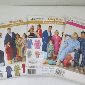 Puede incluir: Tres sobres de patrones de costura Simplicity con imágenes de personas con batas y pijamas. Los patrones están etiquetados como "easy-to-sew" y "Learn to Sew". Los patrones incluyen tallas A-XS/XL y son para batas y ropa de dormir.