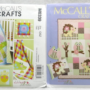 May include: Two McCall's Crafts sewing pattern envelopes. The left envelope features a baby quilt with animal appliqués, a bib, and a framed giraffe. The right envelope shows a quilt with hedgehogs, owls, and trees.