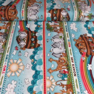 May include: A light blue fabric roll featuring a colorful print of Noah's Ark, animals, rainbows, and the sun. The design includes text that reads "Noah's Ark", "Promise", "Peace", and "Look for the Rainbow". The fabric is suitable for various craft projects.