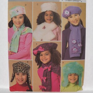 May include: A variety of children's winter hats and scarves. Styles include a leopard print trapper hat, a fuzzy teal hat, a white fur hat and scarf set, a purple beret and scarf with floral accents, a plaid hat and scarf set with pink bows, and a pastel hat and scarf set.