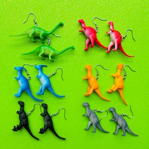 Pode incluir: Um conjunto de 10 pares de brincos de dinossauro. Os brincos são feitos de plástico e vêm em uma variedade de cores, incluindo verde, vermelho, azul, laranja, preto e cinza. Cada par de brincos apresenta um design de dinossauro diferente.