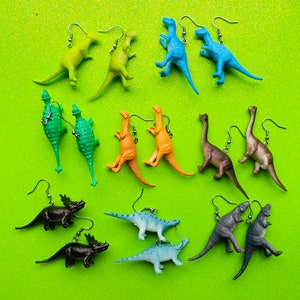 Pode incluir: Um conjunto de 12 pares de brincos de dinossauro. Os brincos são feitos de plástico e apresentam uma variedade de designs de dinossauros, incluindo um T-Rex, Triceratops, Stegosaurus, e muito mais. Os brincos estão disponíveis em uma variedade de cores, incluindo verde, azul, laranja e marrom.