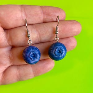 Pode incluir: Um conjunto de três canecas de cerâmica com uma cobertura creme salpicada. Cada caneca apresenta um design floral pintado à mão em tons de azul, verde e amarelo. As canecas têm uma forma simples e arredondada e uma pega confortável.