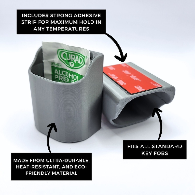 May include: A gray, 3D-printed key fob holder with a strong adhesive strip. The holder includes the text "INCLUDES STRONG ADHESIVE STRIP FOR MAXIMUM HOLD IN ANY TEMPERATURES" and "FITS ALL STANDARD KEY FOBS". It is made from ultra-durable, heat-resistant, and eco-friendly material.
