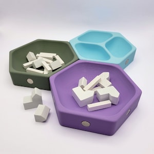 May include: Three hexagonal shaped bowls, one green, one light blue, and one purple, with white wooden pieces inside. The bowls are made of plastic and have a smooth, matte finish.