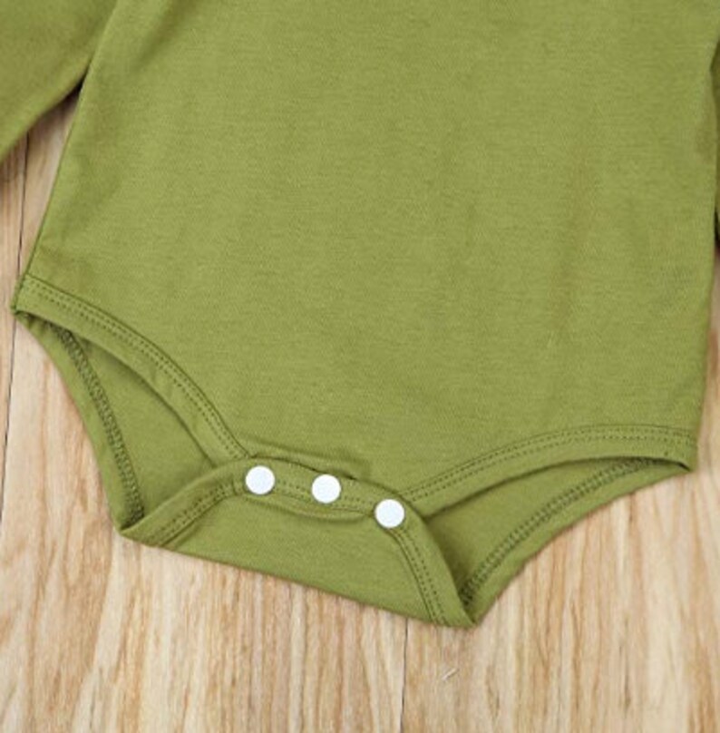 Op de afbeelding: Een groene longsleeve bodysuit met witte drukknoopjes aan de onderkant.