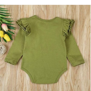 Op de afbeelding: Een groene baby romper met lange mouwen en geruite mouwen.