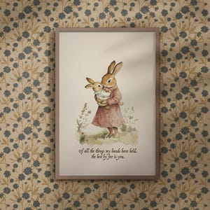 May include: Framed watercolour print depicting two rabbits. One rabbit holds a smaller rabbit. The larger rabbit wears a pink dress. The print includes the text: "Of all the things my hands have held, the best by far is you."