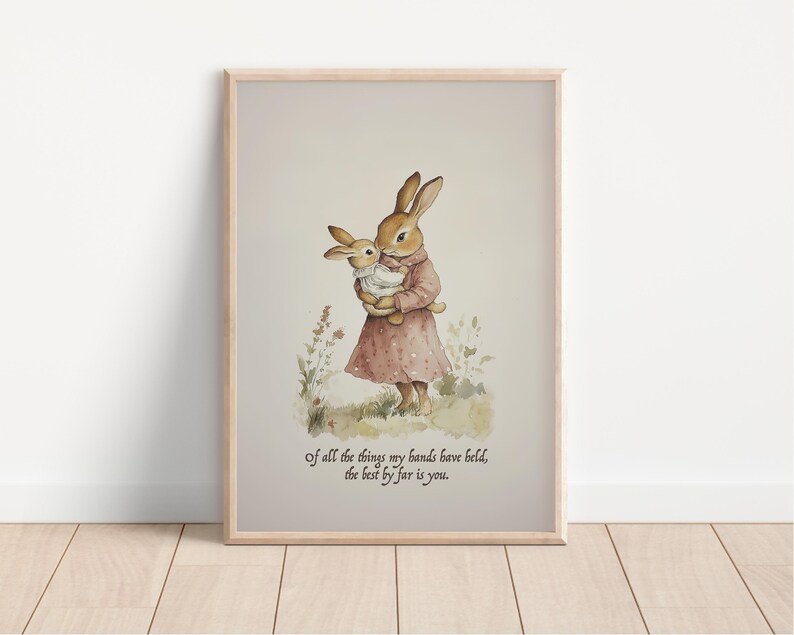 May include: Watercolor print of two rabbits, one holding the other. The rabbits are in a field of grass and flowers. The print is in a wooden frame. Text at the bottom reads: "of all the things my hands have held, the best by far is you."