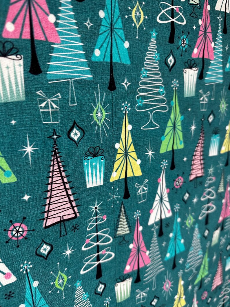 Puede incluir: Tela turquesa con un patr&oacute;n repetido de &aacute;rboles de Navidad estilizados en rosa, amarillo, azul y blanco. Los &aacute;rboles tienen un dise&ntilde;o retro moderno de mediados de siglo con formas geom&eacute;tricas y l&iacute;neas. El fondo es de color turquesa oscuro con estrellas blancas.