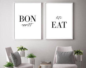 May include: Two black and white framed prints with the text "Bon appetit" and "Let's Eat" hanging on a gray wall above two white chairs with black and white striped pillows.