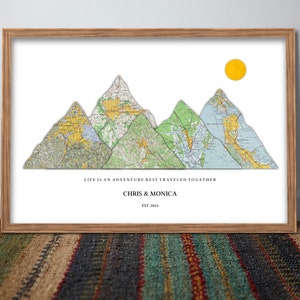 Peut inclure: Une impression encadrée avec une chaîne de montagnes faite de cartes, un soleil jaune et le texte "La vie est une aventure qui se vit mieux ensemble, Chris & Monica, Est. 2024".