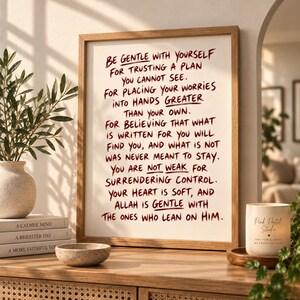May include: A framed wall art print featuring dark red handwritten text on a white background. The text reads: Be gentle with yourself for trusting a plan you cannot see. For placing your worries into hands greater than your own. For believing that what is written for you will find you, and what is not was never meant to stay. You are not weak for surrendering control. Your heart is soft, and Allah is gentle with the ones who lean on Him.
