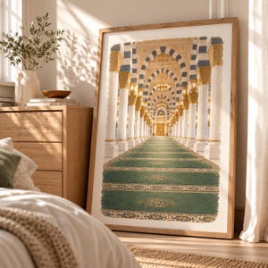 May include: A framed wall art print depicting a long, symmetrical corridor inside a mosque. The scene features rows of white columns with blue and gold accents, a green carpeted floor with intricate patterns, and warm, glowing hanging lanterns.