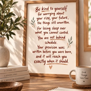 May include: A framed wall art print featuring brown handwritten text that reads: Be kind to yourself for worrying about your rizq, your future, the things still unwritten. For losing sleep over what you cannot control. You are not behind schedule.