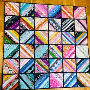 May include: A colourful quilt with a patchwork design. The quilt is made up of many different fabrics, each with a unique pattern. The quilt is a great way to add a touch of personality to any room.